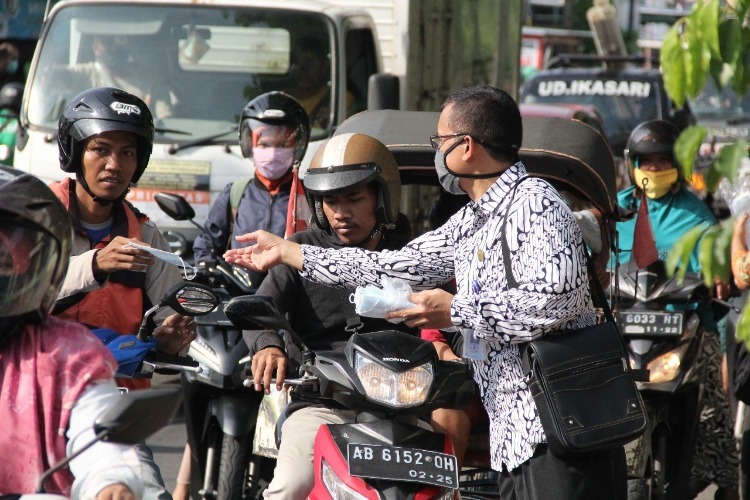 Bapak Cahyo Widayat, S.H., M.Si. selaku Sekretaris Dinas Kebudayaan (Kundha Kabudayan) DIY memberikan masker kepada pengguna sepeda motor yang melintas didekat Pasar Telo